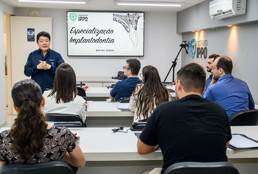 Instrutor falando sobre especialização em Implantodontia com alunos do Instituto IPPO, utilizando slides para ilustrar os conceitos ensinados.