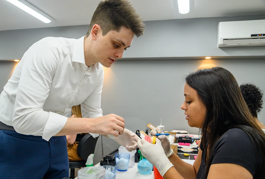 Três participantes concentradas enquanto realizam práticas com materiais odontológicos em um curso do Instituto IPPO.