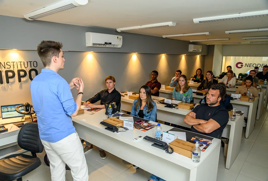 Grupo de pessoas posando para uma foto, incluindo instrutores e participantes do Instituto IPPO, com fundo de painel com logotipos dos patrocinadores.
