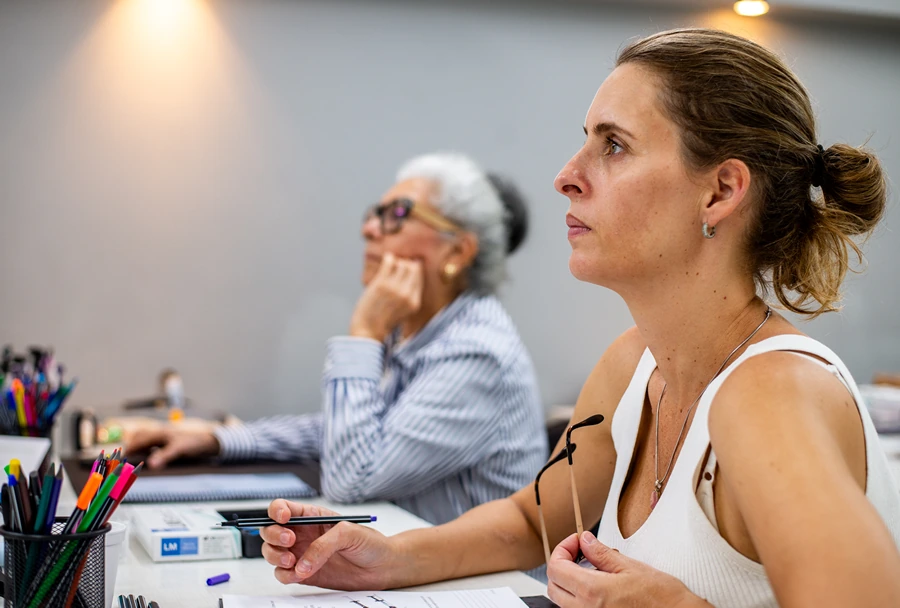 Participante observa atentamente a apresentação durante a mentoria, com foco e dedicação nos detalhes abordados pela instrutora.