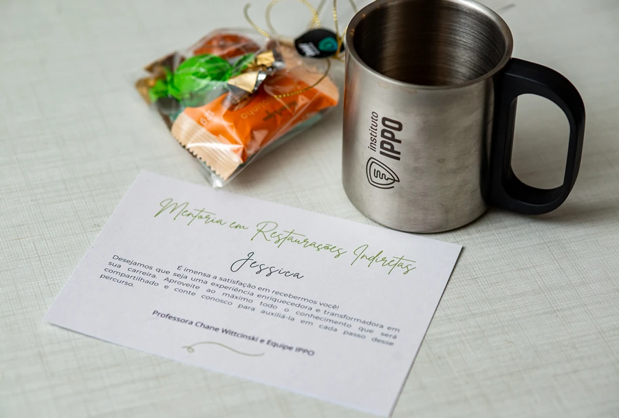 Caneca do Instituto IPPO e cartão de boas-vindas personalizado para a participante, acompanhado de pequenos brindes, representando a recepção especial do curso de mentoria.
